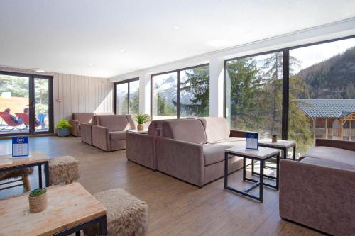 a living room with couches and tables and windows at SOWELL RESIDENCES Pra Loup in Pra-Loup
