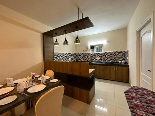 a dining room with a table and chairs and a kitchen at Ponmari Villa in Ooty