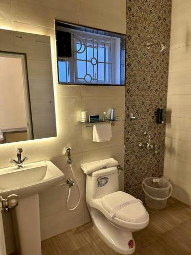a bathroom with a toilet and a sink and a mirror at Ponmari Villa in Ooty