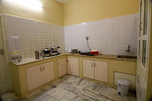 cocina con paredes amarillas y azulejos blancos en Royal Home Stay Gomathipuram, en Madurai