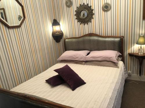 a bed with two pillows on it in a bedroom at Les Fleurs De Lys, Villa Chic L'enclos Des Lys, Proche de la Mer, Linge Inclus in Saint-Georges-dʼOléron