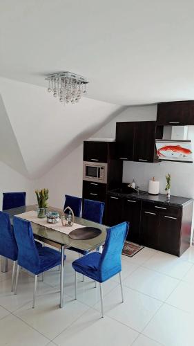 a kitchen with a dining table and blue chairs at Sunset Beach in Sarbinowo