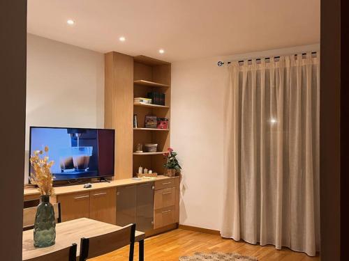 een woonkamer met een televisie en een tafel met stoelen bij Piso céntrico y acogedor in Figueres