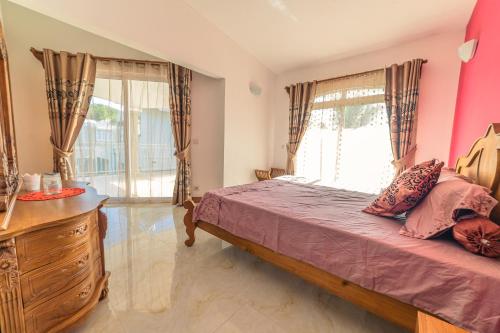 a bedroom with a bed with pink walls and windows at Tropicana Villa in Le Morne