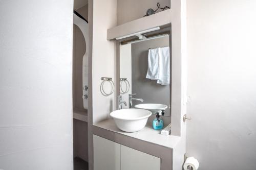 W łazience znajduje się biała umywalka i lustro. w obiekcie Aiolos loft sea view peiraiki w Pireusie