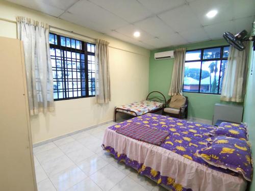a bedroom with a bed and a chair and windows at Cosy Homestay Ulu Tiram in Ulu Tiram