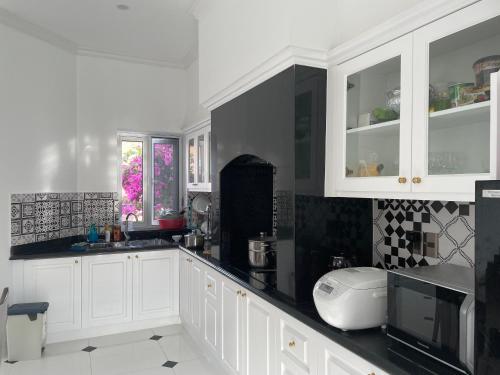 a kitchen with white cabinets and black and white tiles at Hoa Tien Paradise Villa in Ha Tinh