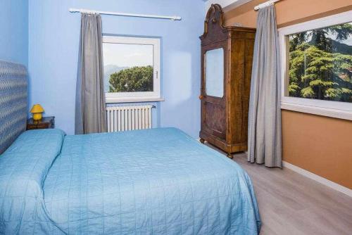 a blue bedroom with a bed and a window at Villa Gardesana Torri del Benaco in Torri del Benaco