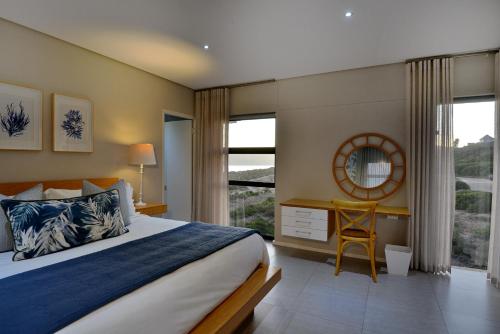a bedroom with a bed and a desk and a window at The Shark Bay Boutique Hotel & Spa in Langebaan