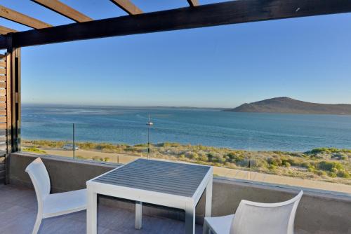 a table and chairs on a balcony with a view of the ocean at The Shark Bay Boutique Hotel & Spa in Langebaan