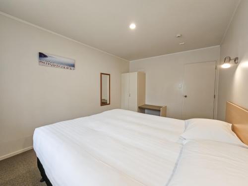 a bedroom with a large white bed in it at Captain Cook Motor Lodge in Gisborne
