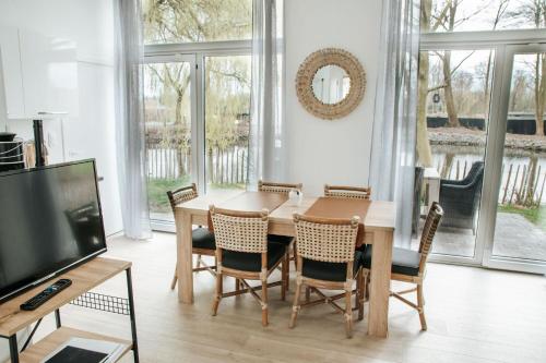 una sala da pranzo con tavolo, sedie e TV di Trendy chalet aan visvijver a Hamme