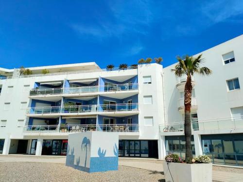 a white building with a palm tree in front of it at Grand F2 Bastia Centre Port de Toga, Terrasse Vue Mer in Bastia