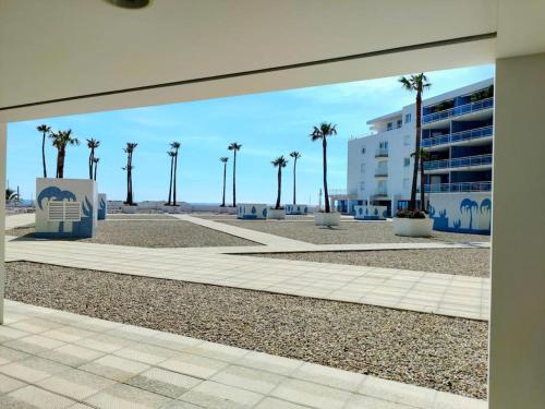 a view of a beach with palm trees and a building at Grand F2 Bastia Centre Port de Toga, Terrasse Vue Mer in Bastia
