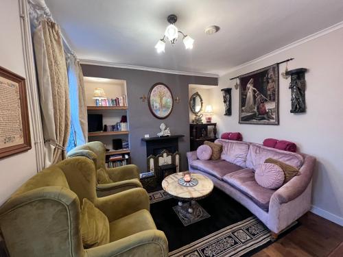 a living room with a couch and two chairs at Glastonbury Rose Cottage - Magical Victorian Town Centre Stay in Glastonbury