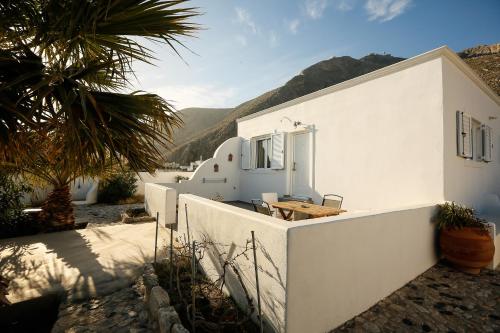 una casa blanca con una valla y una palmera en Thera cycladic house at Perissa , Santorini by MPS, en Perissa