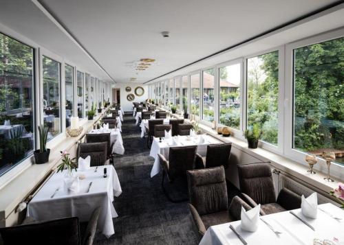 een restaurant met tafels, stoelen en ramen bij Hotel Weserschlösschen in Nienburg