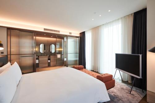 a bedroom with a large white bed and a flat screen tv at Nine Tree Premier ROKAUS Hotel Seoul Yongsan in Seoul