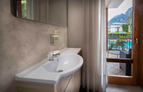 a bathroom with a sink and a mirror and a window at SunLake Hotel in Riva del Garda