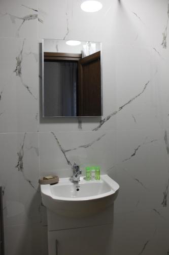 een witte badkamer met een wastafel en een spiegel bij Orange House in the Old Town Plovdiv in Plovdiv