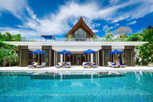 a villa with a swimming pool and blue umbrellas at Kon Sang Villa in Patong Beach