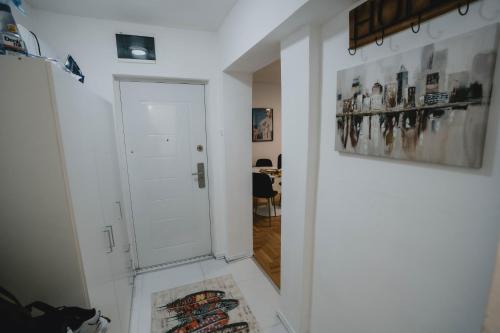 un pasillo con una puerta blanca y una mesa en Apartman Daris 2 en Sarajevo