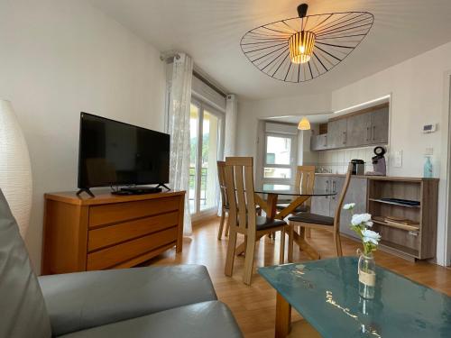 un salon avec une télévision et une table avec des chaises dans l'établissement Le brin d'osier, à Kaysersberg