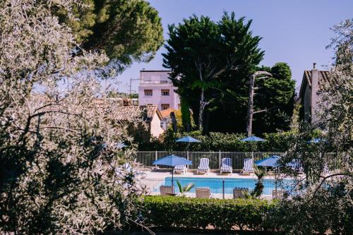 Elle offre une vue sur la piscine bordée de chaises et de parasols. dans l'établissement Eden Azur, au Golfe-Juan