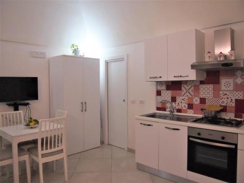 kuchnia z białymi szafkami, stołem i kuchenką w obiekcie Casa dei Gemelli w mieście Minori