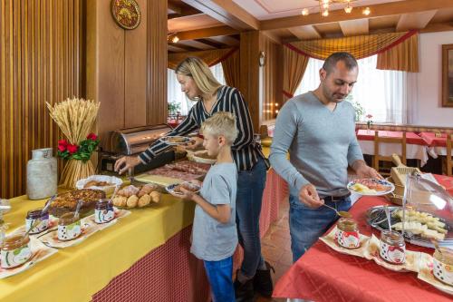 una famiglia che si trova di fronte a un tavolo con cibo di Hotel Bonapace ***S a Madonna di Campiglio