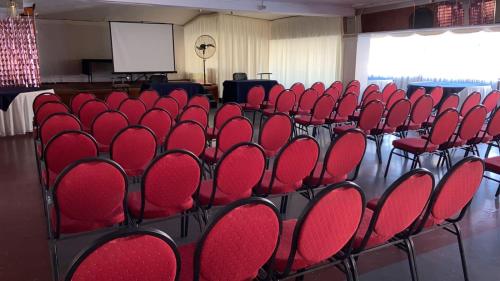 a row of red chairs in a room with a screen at NEW HOTEL CRUZ DEL SUR in Concepción
