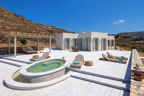 a patio with a hot tub and chairs and a house at Syros Grace eco-Villa with Jacuzzi & Stuning Views in Ano Syros