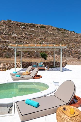 a patio with chairs and a swimming pool at Syros Grace eco-Villa with Jacuzzi & Stuning Views in Ano Syros