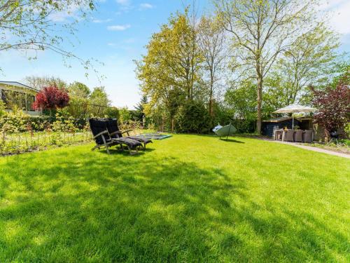 a yard with two chairs in the grass at Luxury chalet near Ouddorp with garden in Goedereede