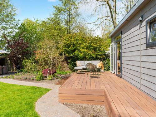 a wooden deck with a couch and a chair on a house at Luxury chalet near Ouddorp with garden in Goedereede