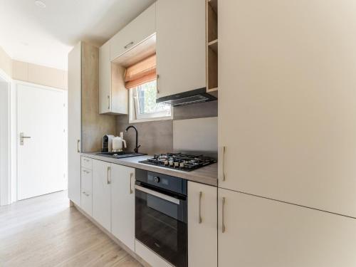 a kitchen with white cabinets and a stove top oven at Luxury chalet near Ouddorp with garden in Goedereede