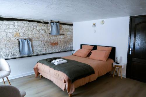 1 dormitorio con cama y pared de piedra en Les chambres du Roc, en Le Roc