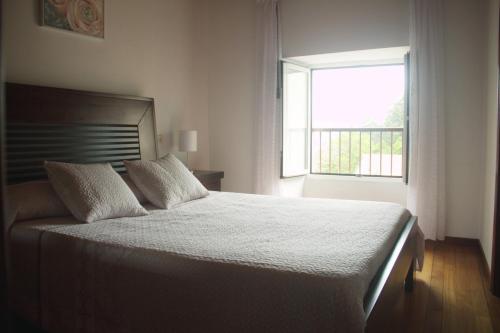 um quarto com uma cama grande e uma janela em Casa da Castañuela em Muros