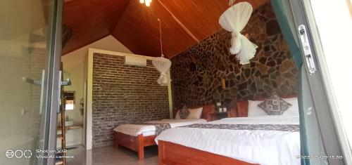 um quarto com 2 camas e uma parede de tijolos em Mai Chau Hillside Homestay em Mai Châu