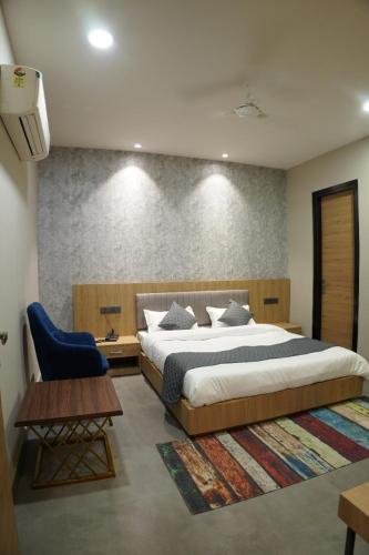 a bedroom with a large bed and a blue chair at HOTEL CENTRAL PARK in Bathinda