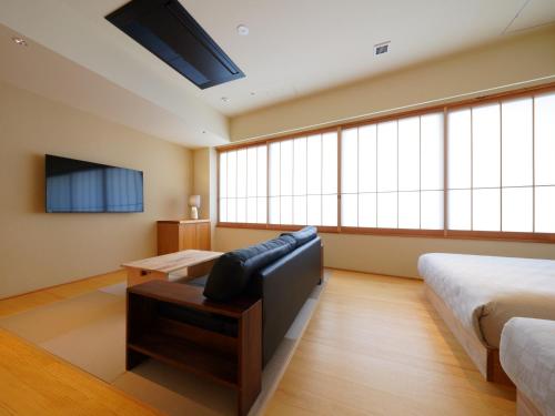 a bedroom with two beds and a couch and a tv at MURE Beppu in Beppu