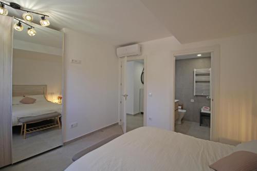 - une chambre blanche avec un lit et un miroir dans l'établissement Apart-rent Apartment Mimoses 0069, à Empuriabrava