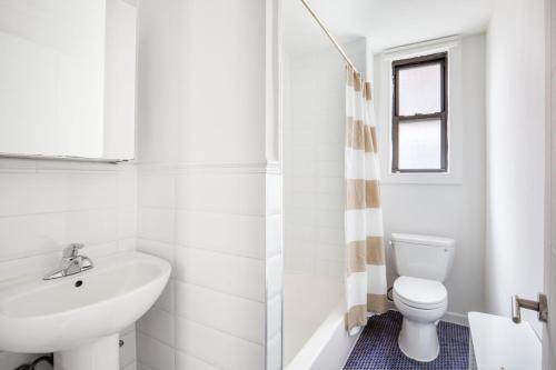 a white bathroom with a sink and a toilet at Midtown 2br w doorman wd nr Central Park NYC-1144 in New York