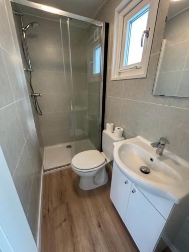 La salle de bains est pourvue de toilettes, d'un lavabo et d'une douche. dans l'établissement Tiny House in de duinen van IJmuiden aan Zee, à IJmuiden