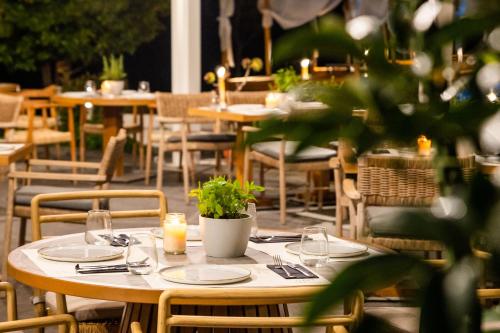 a wooden table with plates and candles on it in a restaurant at Skiathos Avaton Hotel, Philian Hotels & Resorts in Skiathos Town