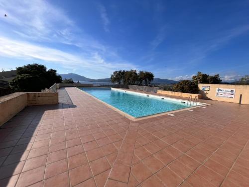 - une piscine sur une terrasse en briques avec un ciel bleu dans l'établissement Kallistea - Appartement avec vue mer, à Porticcio