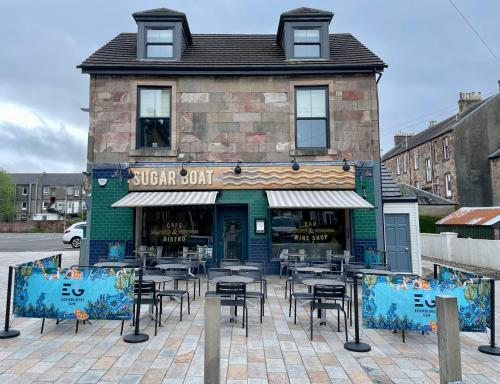 um restaurante com mesas e cadeiras em frente a um edifício em Rooms Above Sugar Boat em Helensburgh