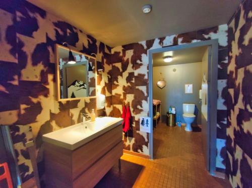 uma casa de banho com um lavatório e uma parede com estampas de vaca em Le sapin rouge, chambres d'hôtes - restaurant - bar em Artigues