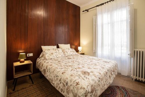 1 dormitorio con 1 cama grande y pared de madera en El Jardí de Can Prat, en Ripoll