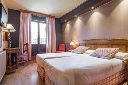 a bedroom with two beds and a desk and a window at Snö Villa de Sallent 3 in Formigal